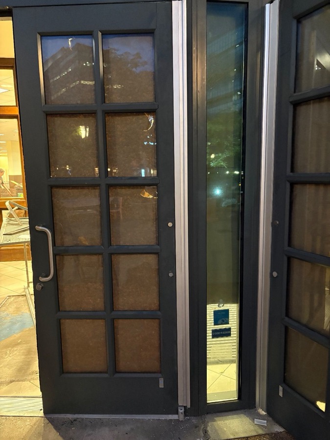 Dark glass commercial entry door with metal handle, photographed at night