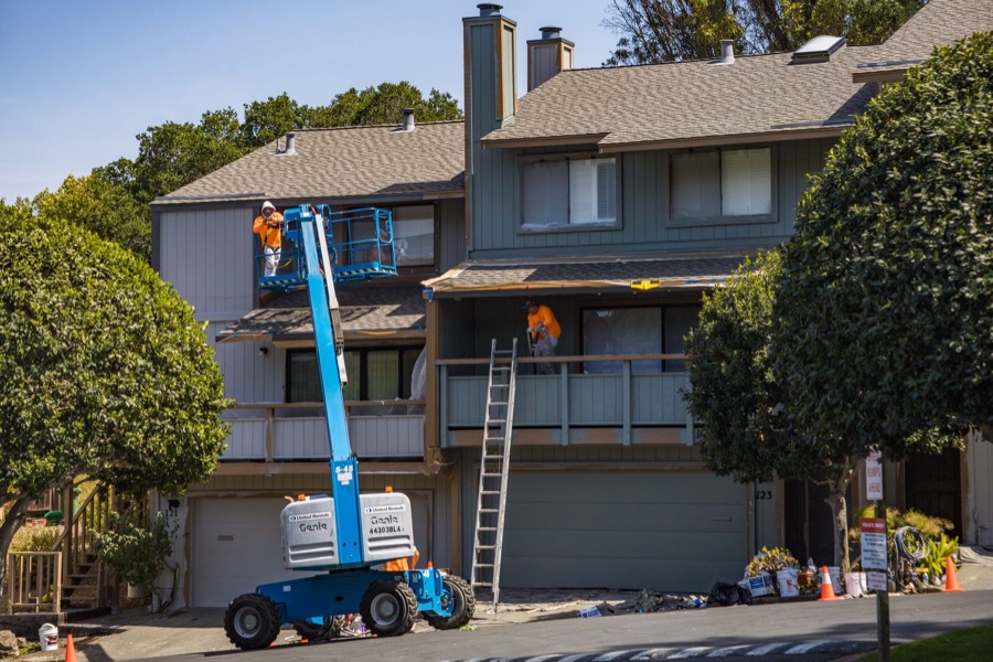 Painting crew on a boom lift working on a multi-story house exterior